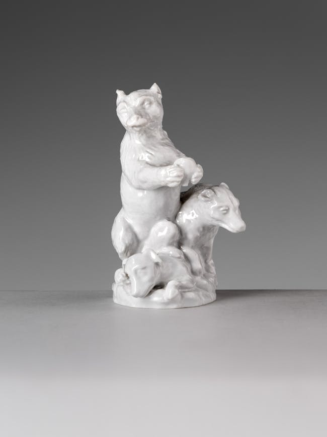 Piccola statua in porcellana bianca raffigurante due orsi che combattono con un cane