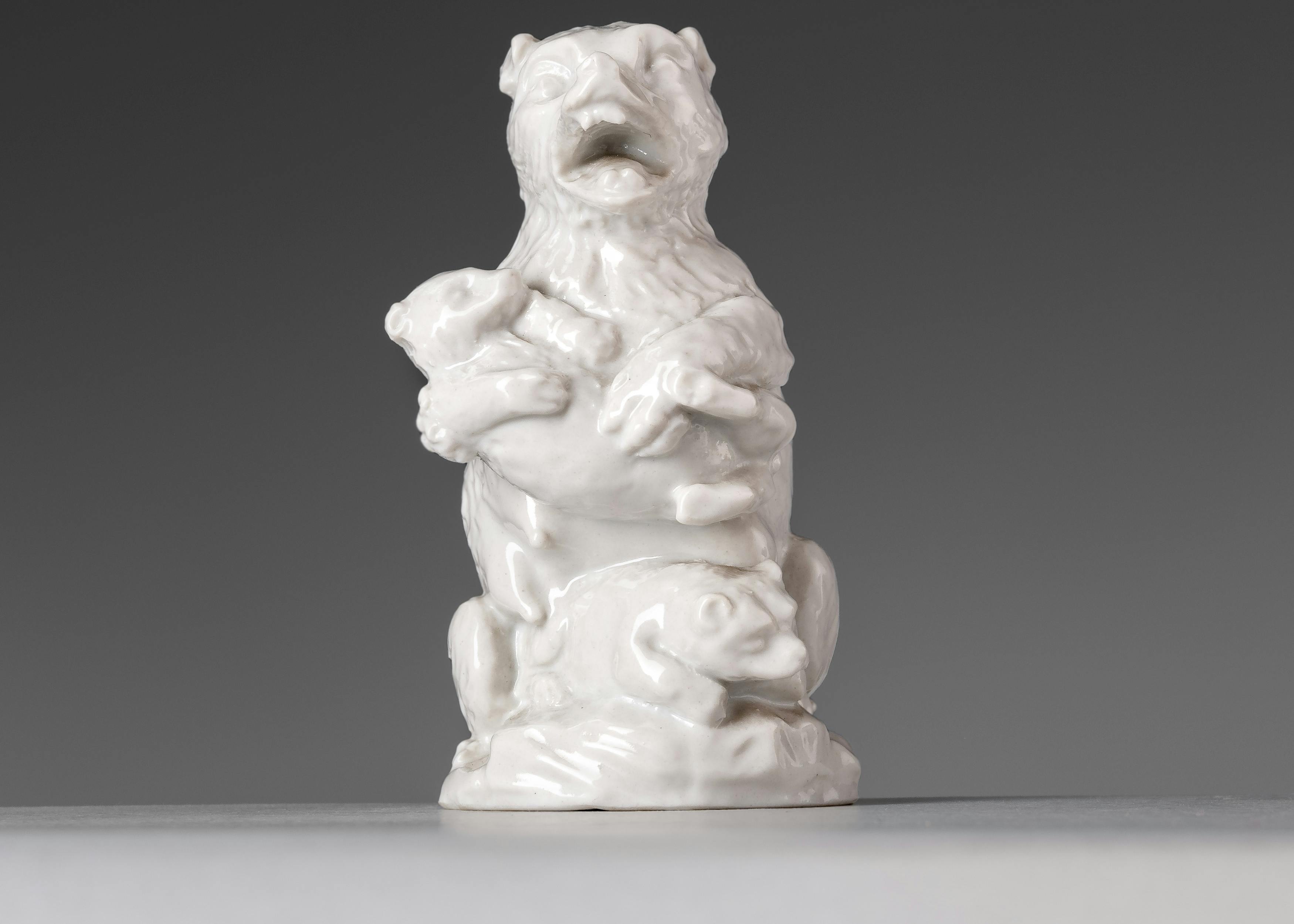 Statuina in porcellana bianca raffigurante un orsa con un cucciolo in braccio e un altro cucciolo ai suoi piedi