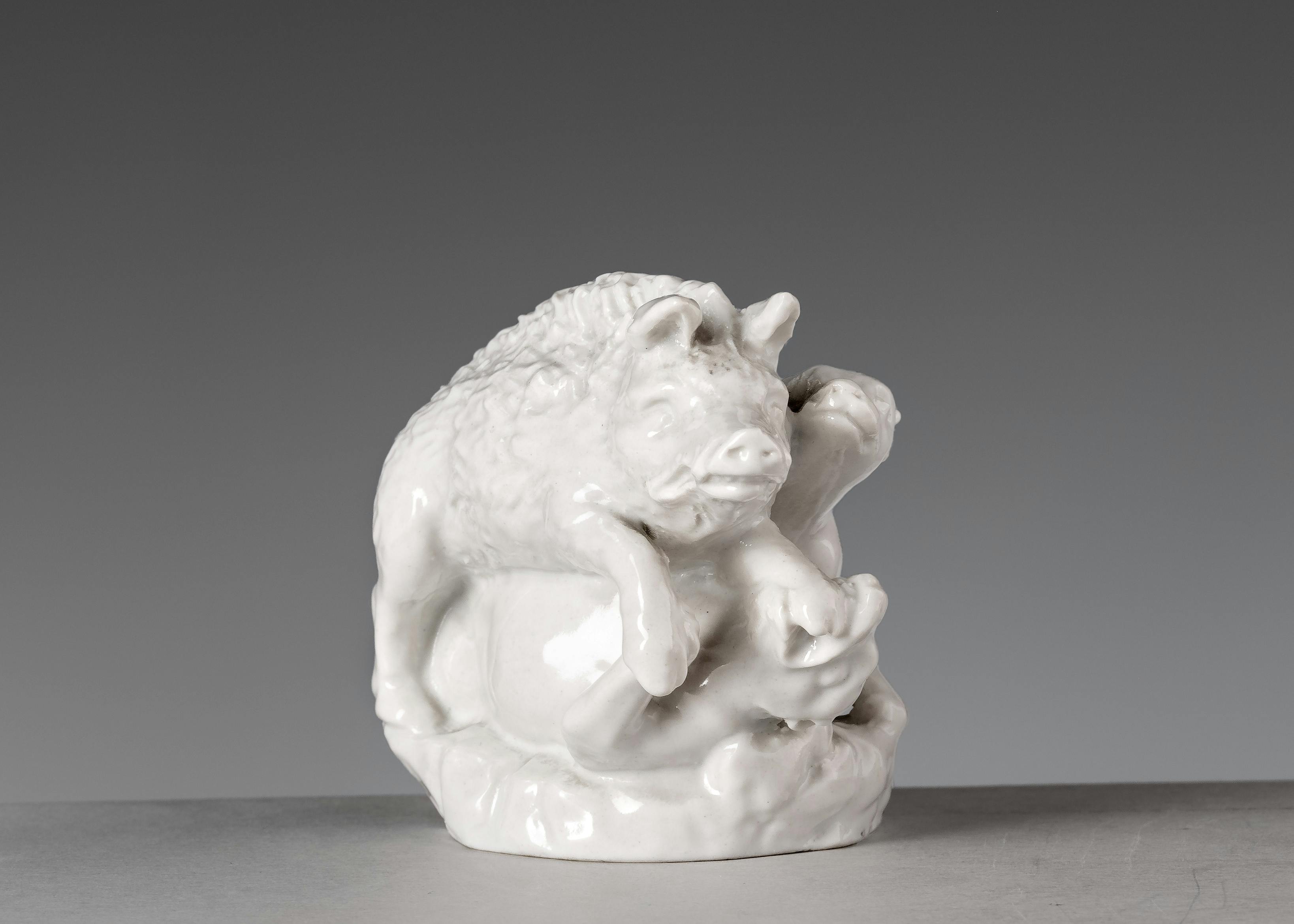 piccola scultura in porcellana bianca raffigurante in cinghiale aggredito da due cani