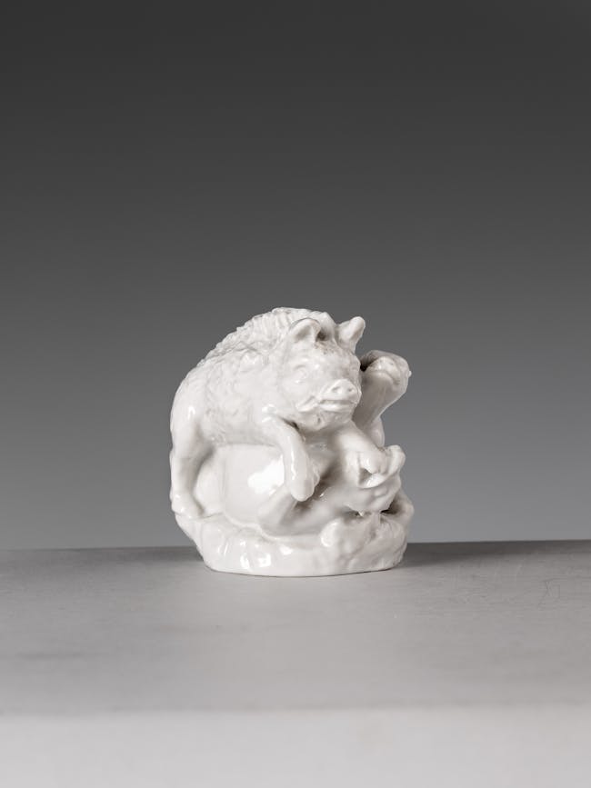 piccola scultura in porcellana bianca raffigurante in cinghiale aggredito da due cani
