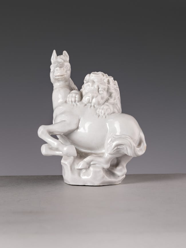 Statuetta in porcellana bianca raffigurante un leone che aggredisce un cavallo
