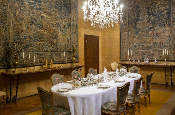 Una vista del tavolo apparecchiato, circondato da pareti decorate con arazzi