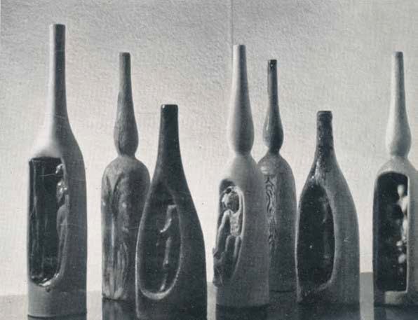 fotografia in bianco e nero di manufatti ceramici a forma di bottiglia con incavo che contiene una figurina