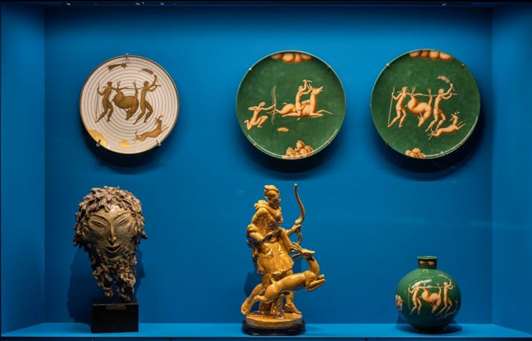 Vetrina con tre piatti, un vaso e due piccole sculture