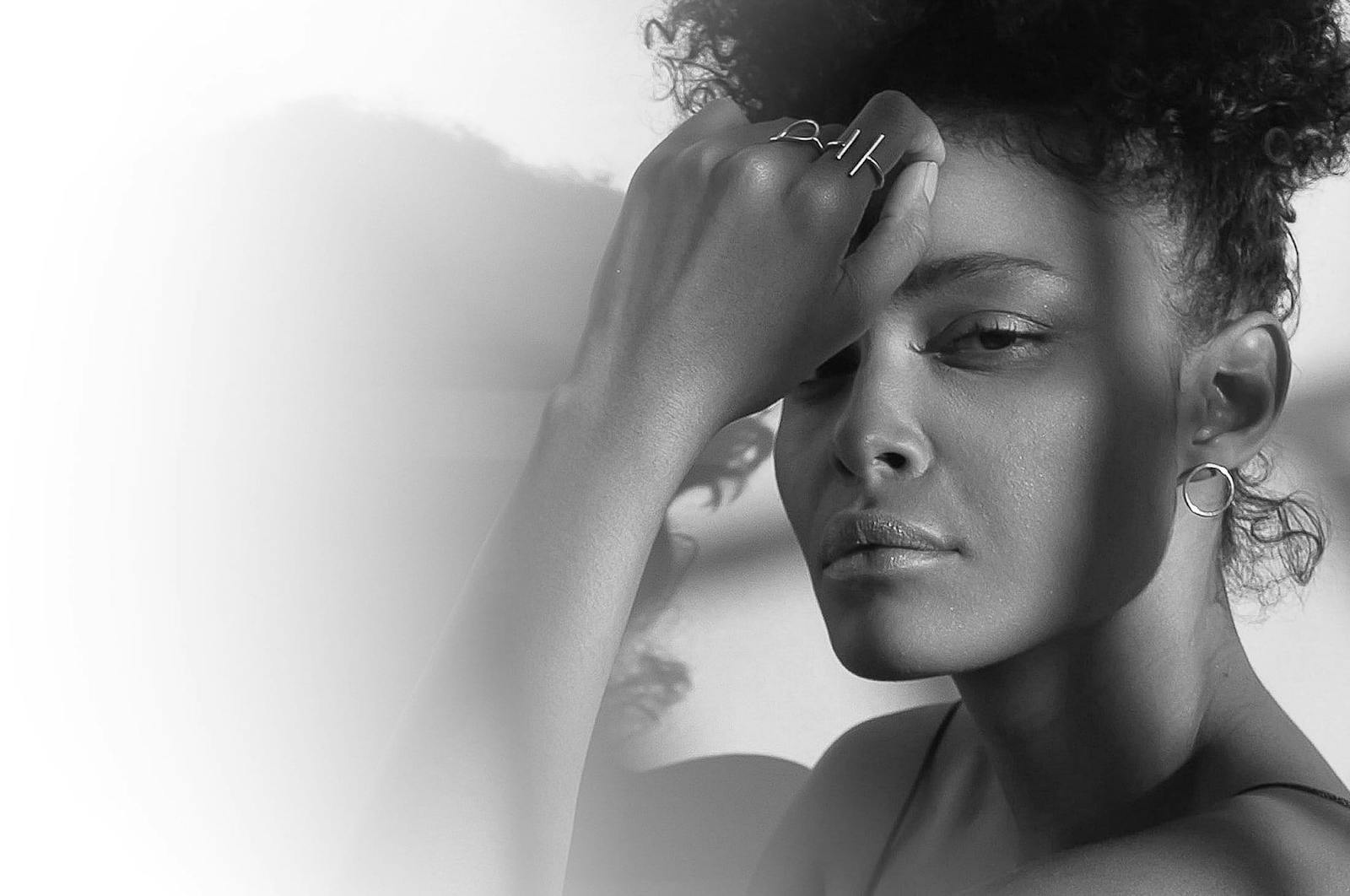 Woman with curly hair in an updo with her hand on her forehead