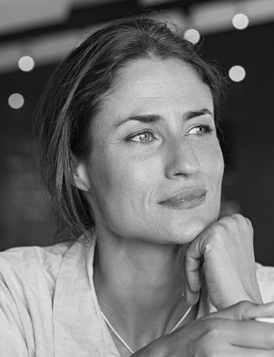 Woman looking to the side with her chin on her knuckles.