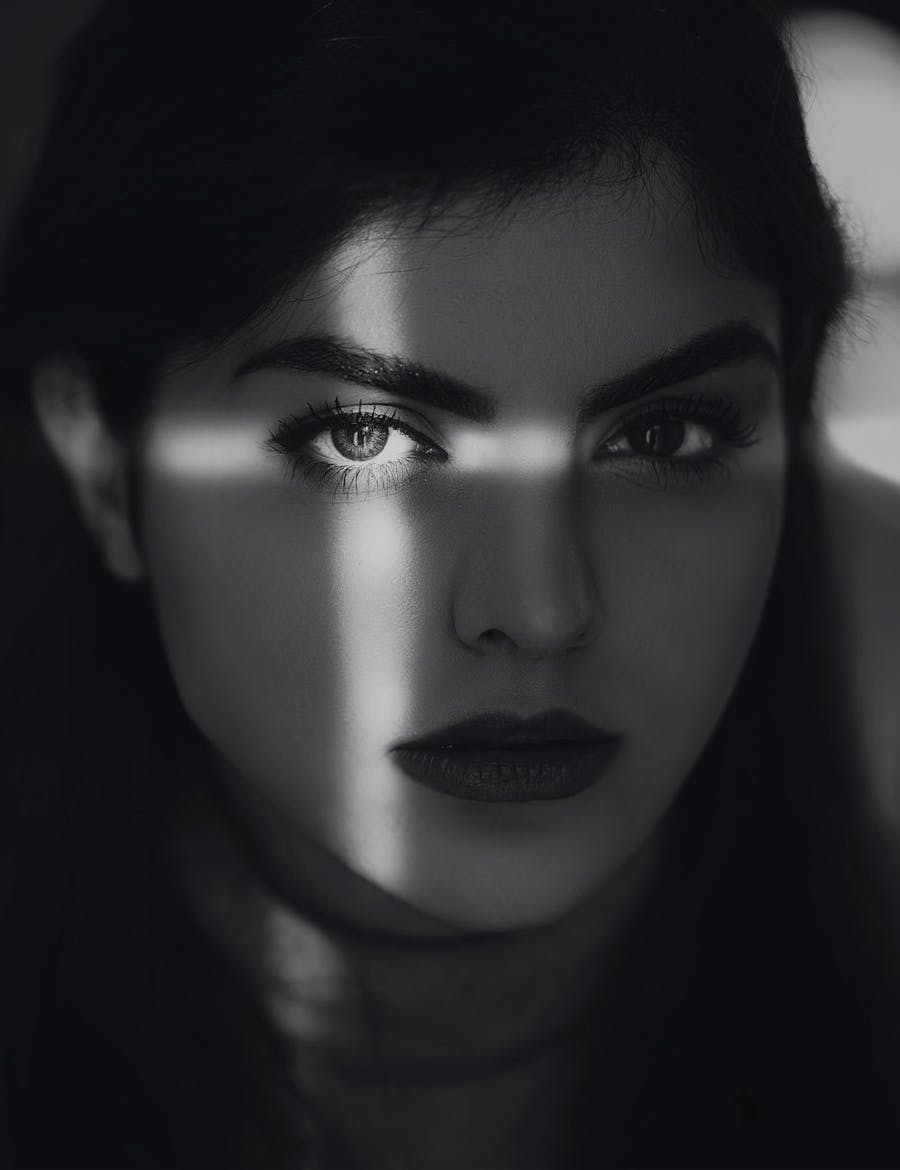 A beautiful woman's shadowed face with light making a cross on her left eye