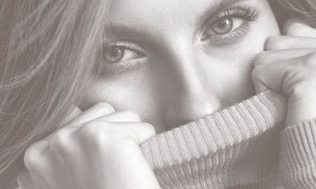 Woman pulling a turtle neck up to her nose.