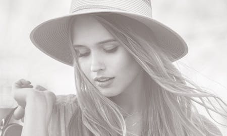 Woman in a brimmed hat looking down.