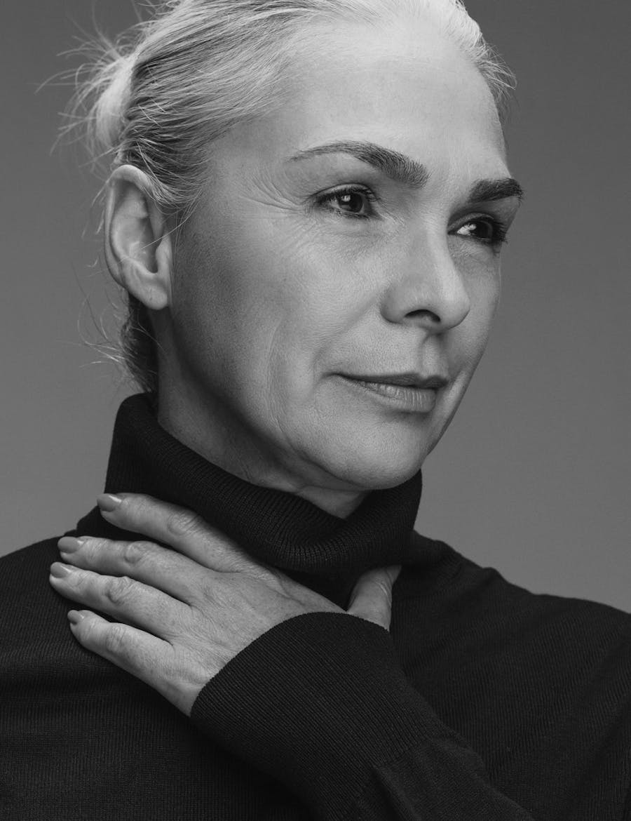 Older woman looking off to the side with one had on her neck.