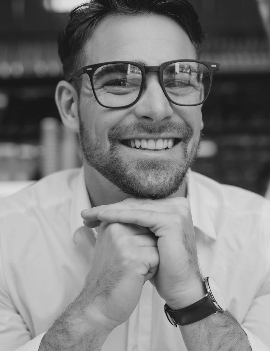 A smiling man with his chin resting on his knuckles.