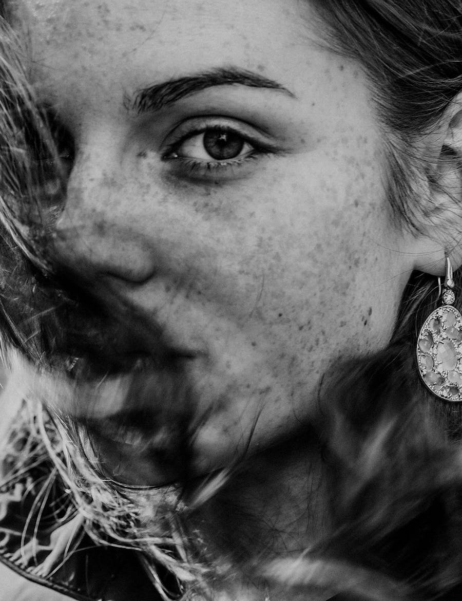 Freckled woman with face half-covered by her hair.