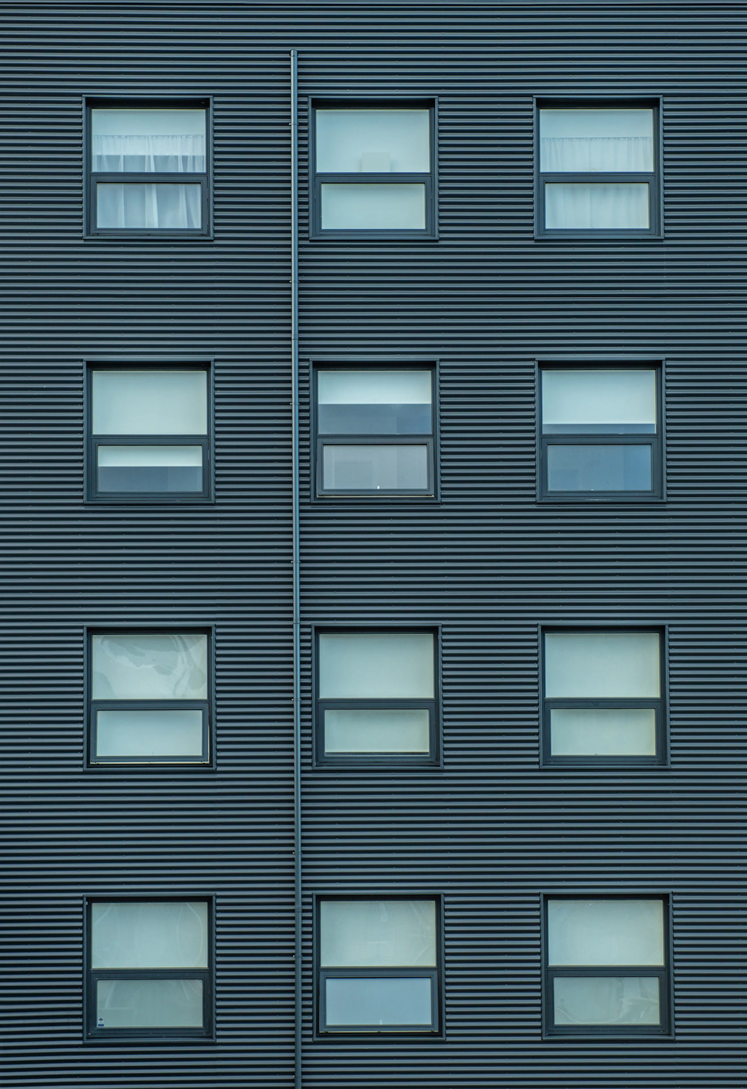 Gluggar í álklæddu fjölbýlishúsi