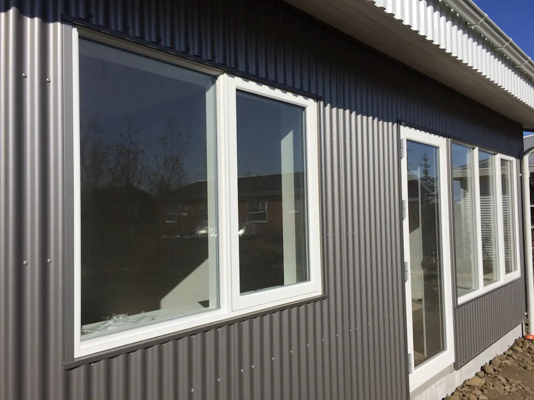 Hvítir PVC á gluggar á bárujárns-klæddu húsi