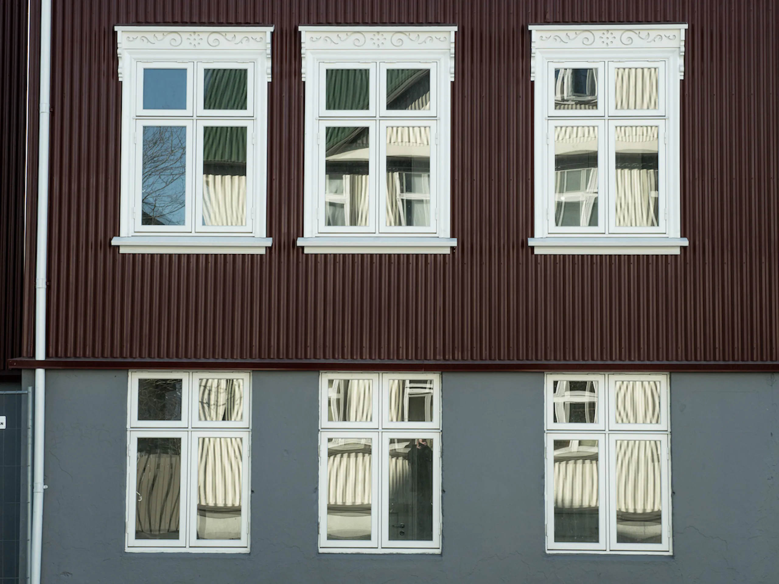 Hvítir aldamótagluggar á bárujárnshúsi með flúri á körmum