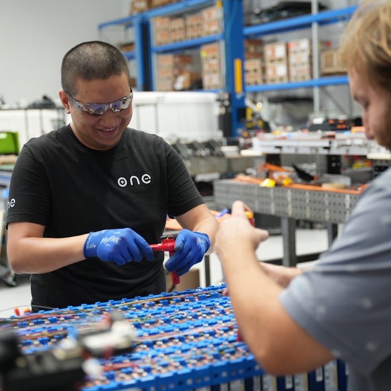 Two production line workers assembling battery packs