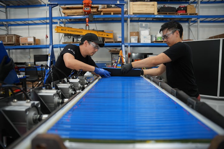 Two production line workers building battery packs