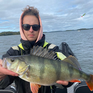 An image of Nathanael van den Berg, Technical Designer for Call of the Wild: The Angler having successfully caught a fish on a boat.