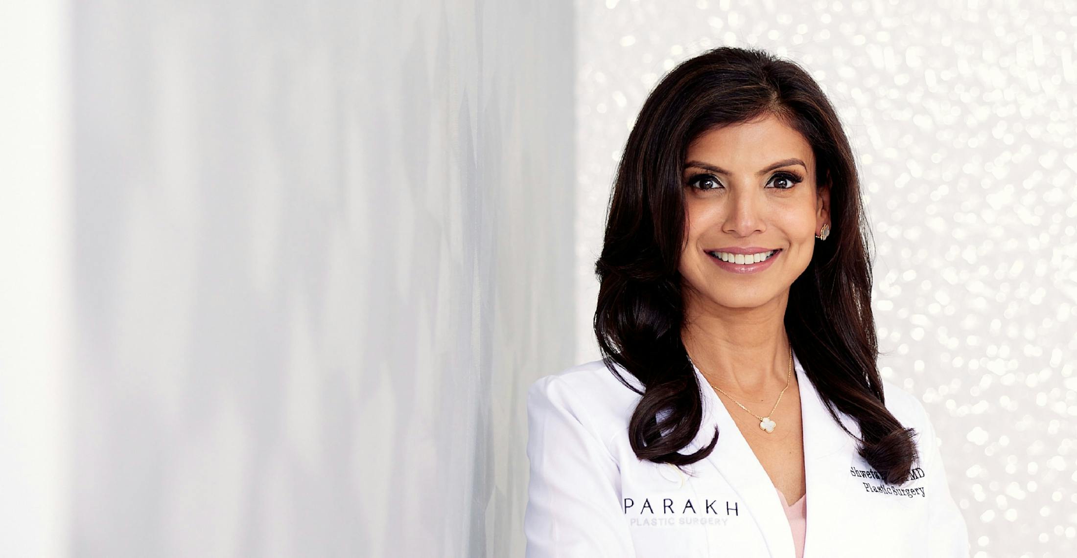 Plastic Surgeon Dr. Parakh leaning on a wall smiling