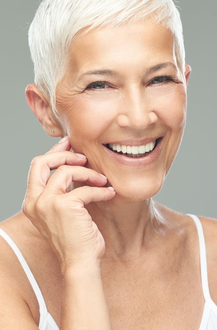 Older woman smiling and touching face