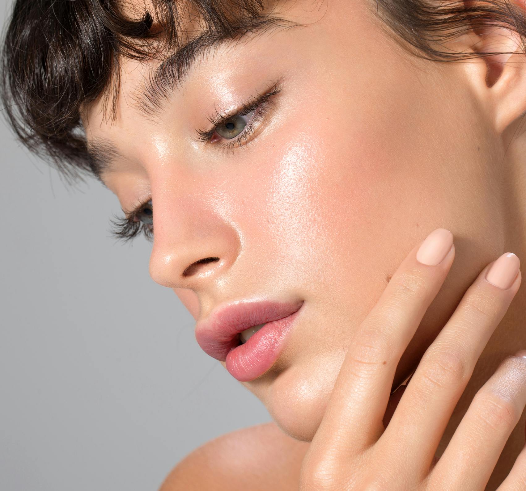 Young brunette woman touching her face.