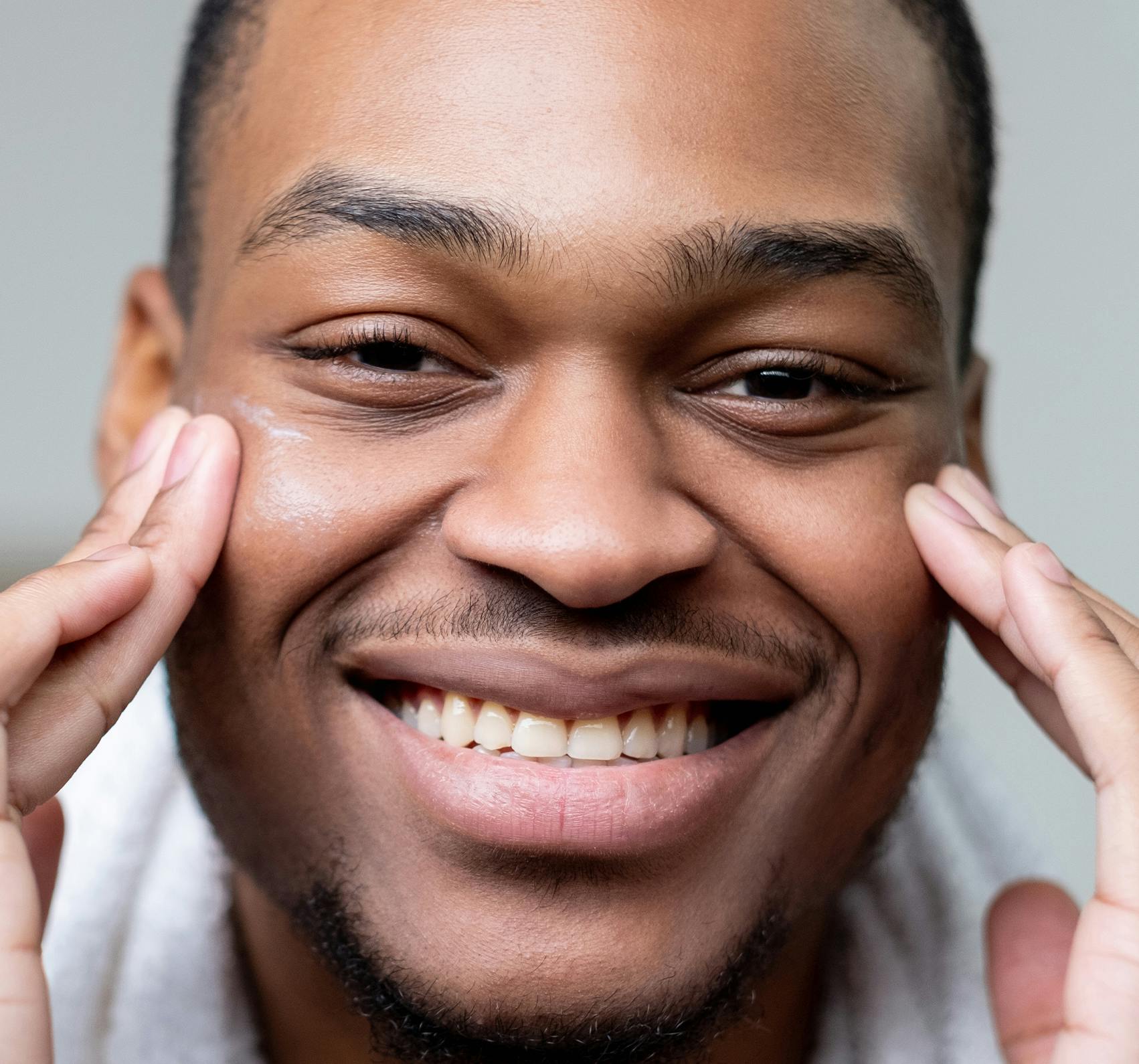 Close up shot of a man touching his face.