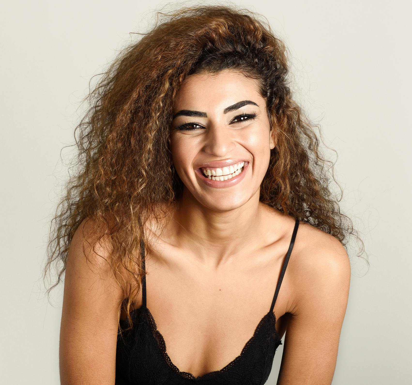 Frizzy haired woman in a black top smiling towards the camera.
