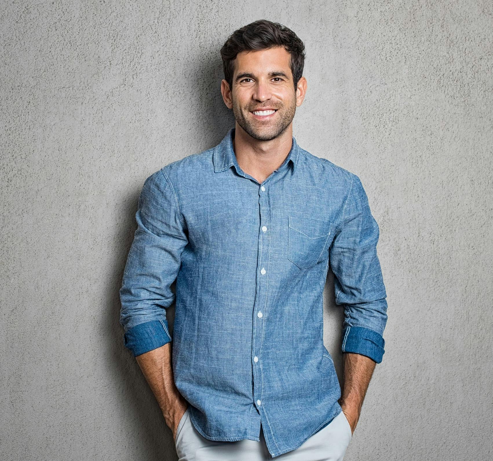 Man in a blue jean jacket against a gray backdrop.