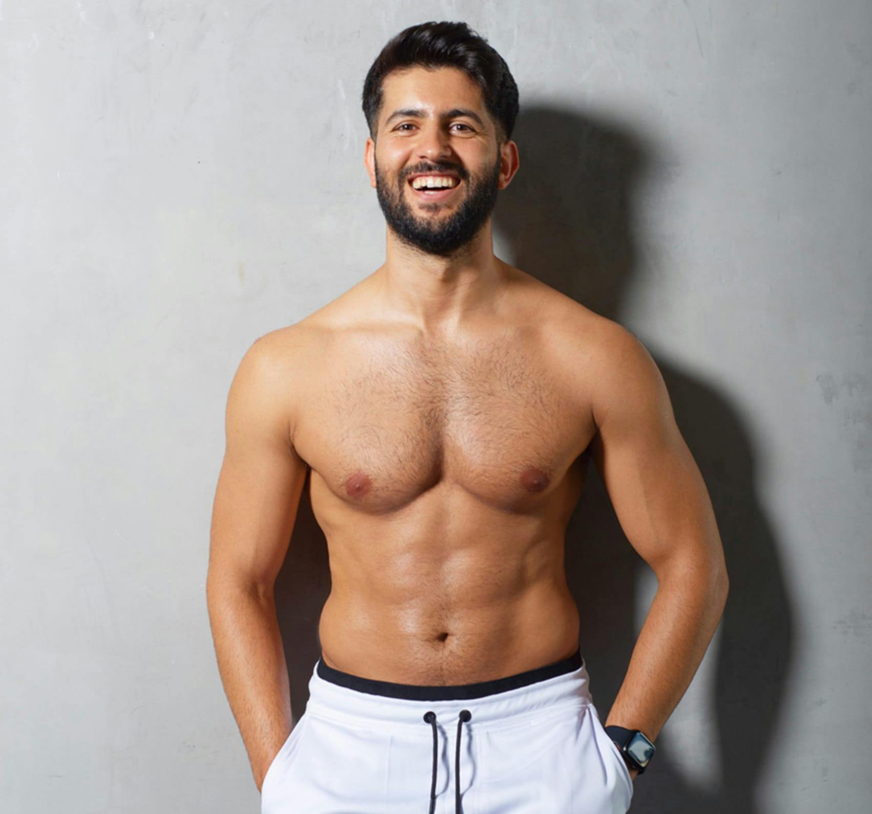 Smiling shirtless man wearing white gym shorts.