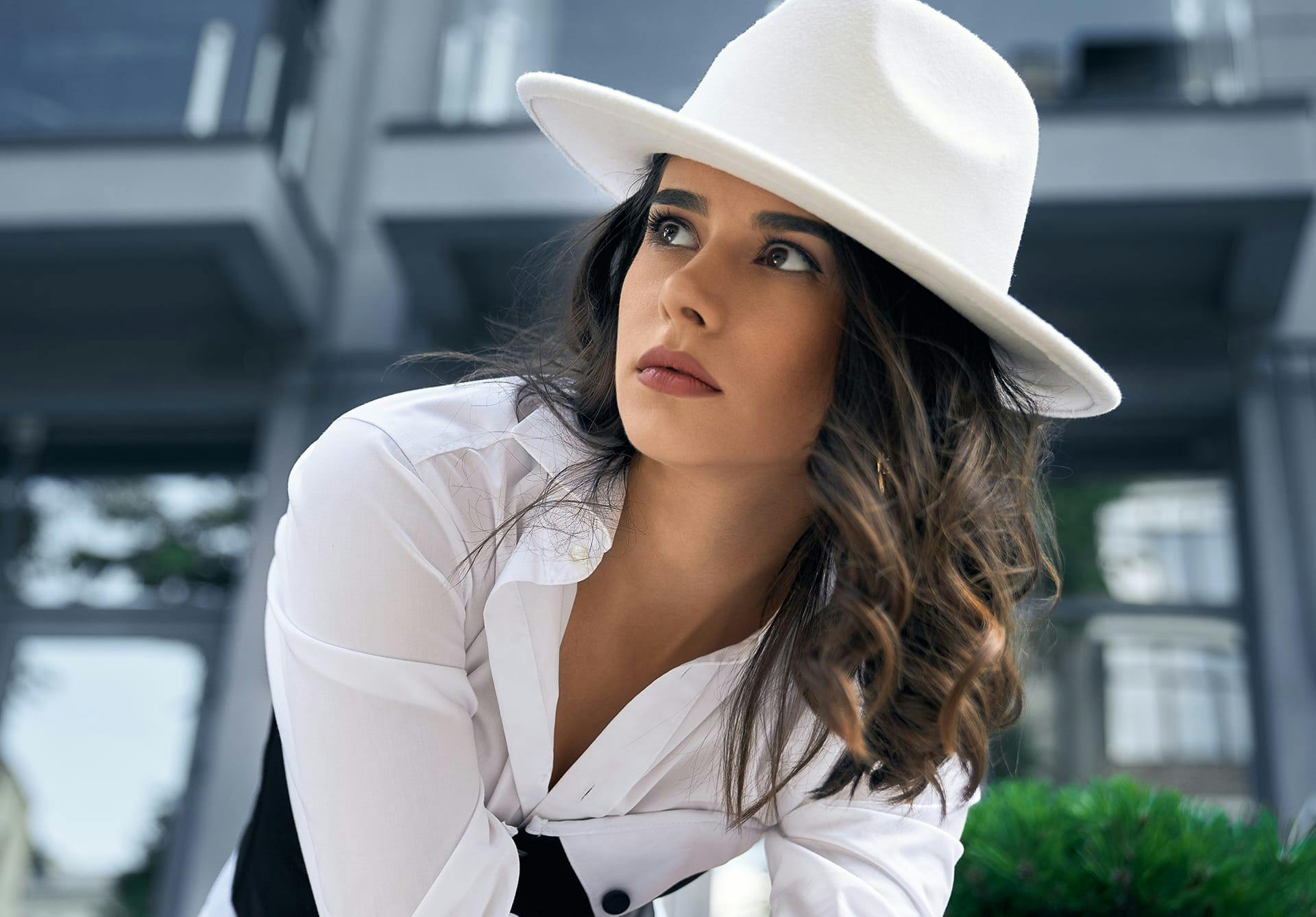 Woman with beautiful lips wearing a white hat and looking towards the sky.