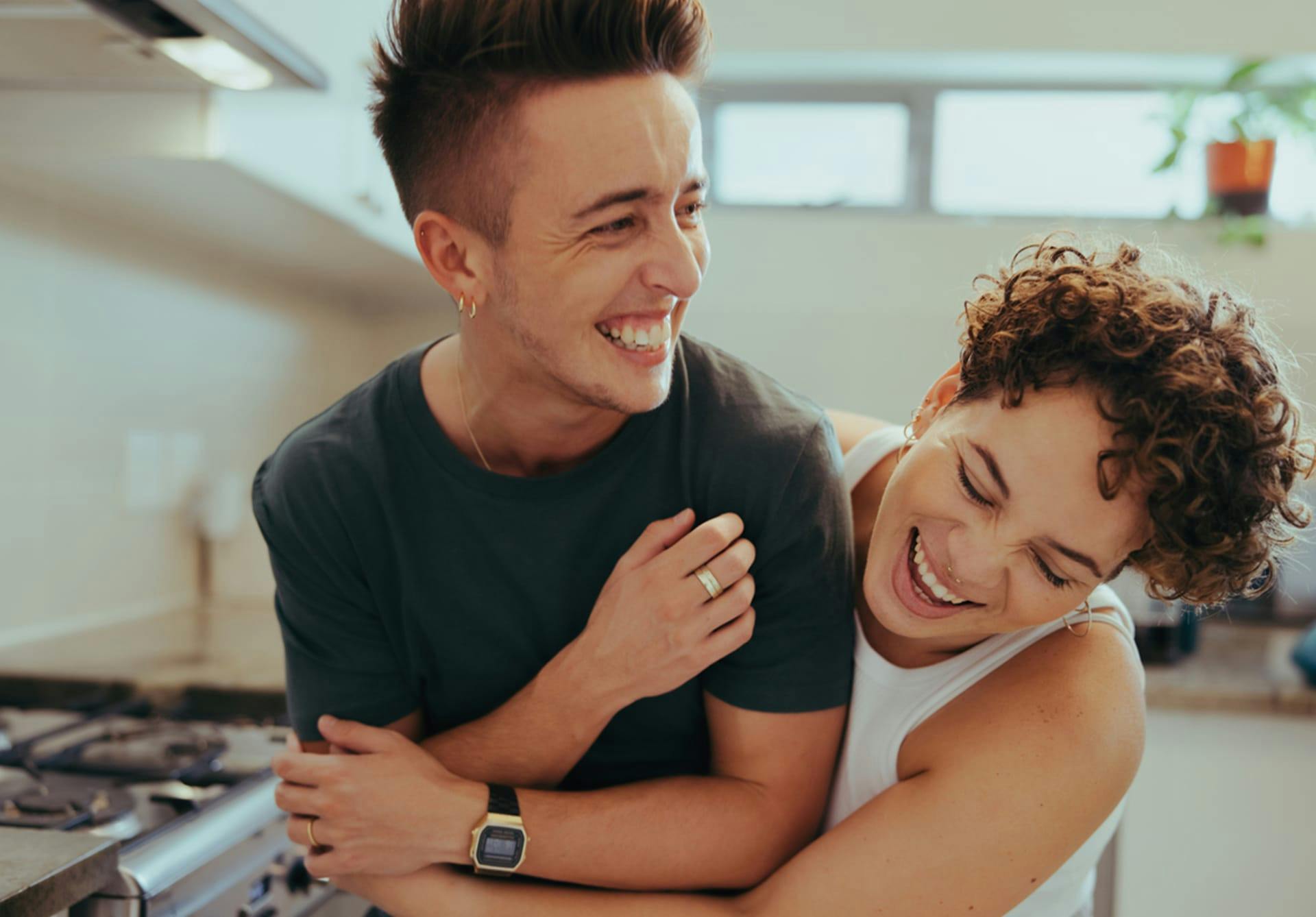 a couple hugging and laughing in a kitchen