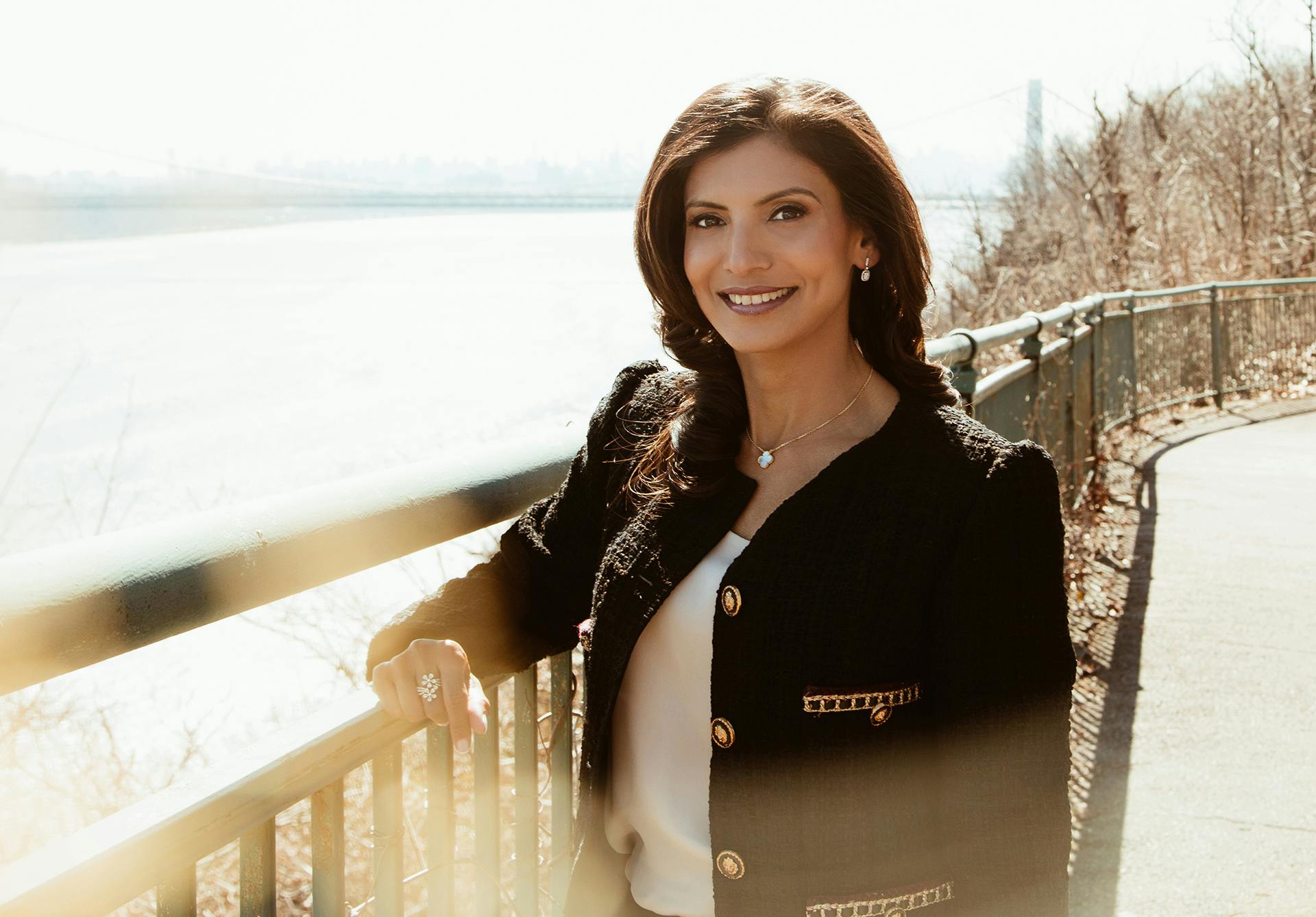an image of Dr. Parakh smiling in a black blazer and white top by the water