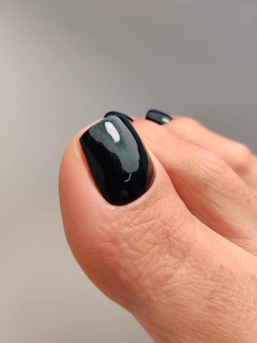 Dark cat eye pedicure with a green tint