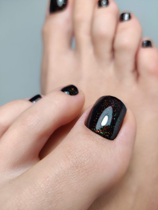 Dark glossy pedicure with bright sparkles