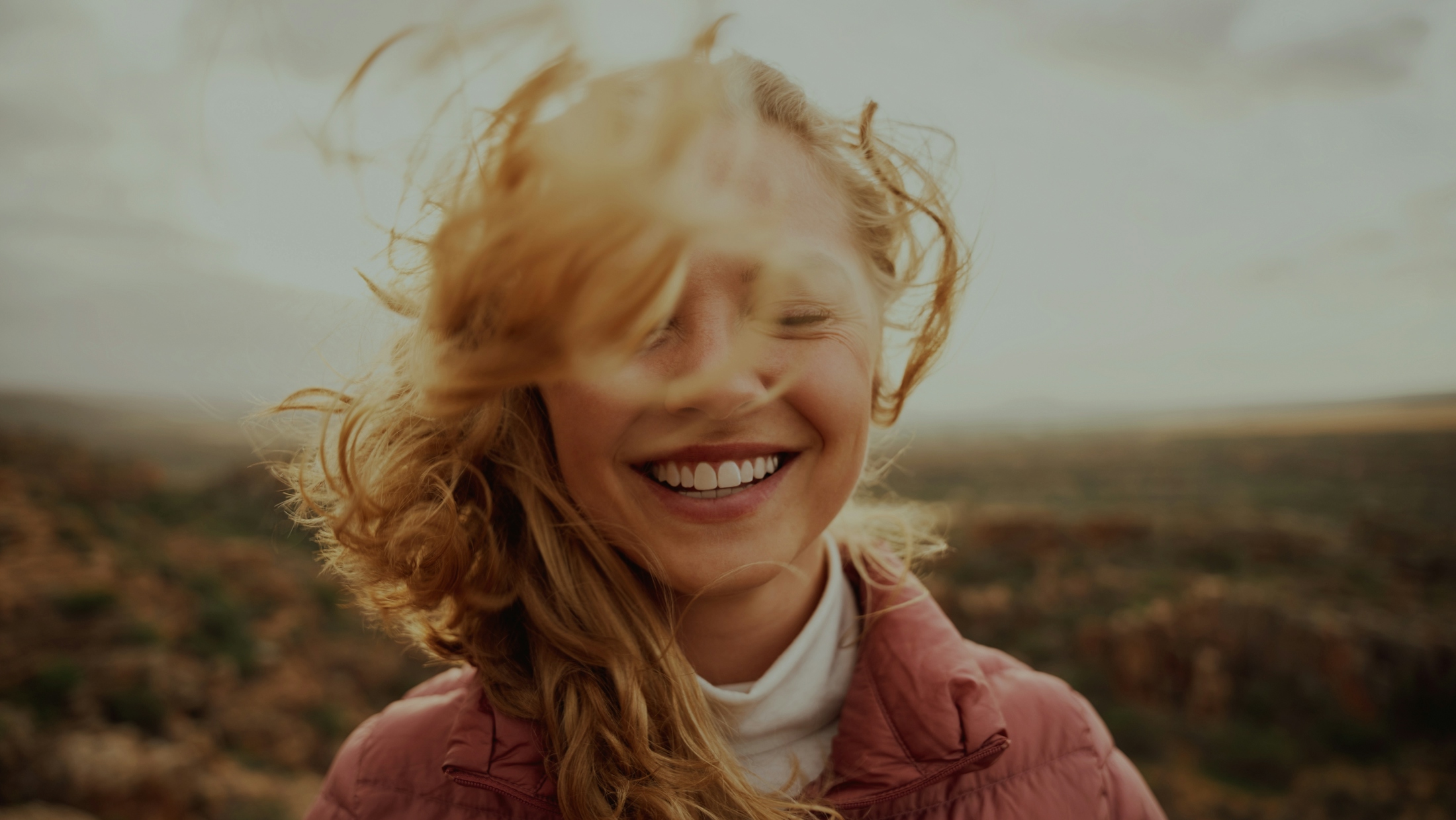 Girl smiling with the wind blowing her hair in her face