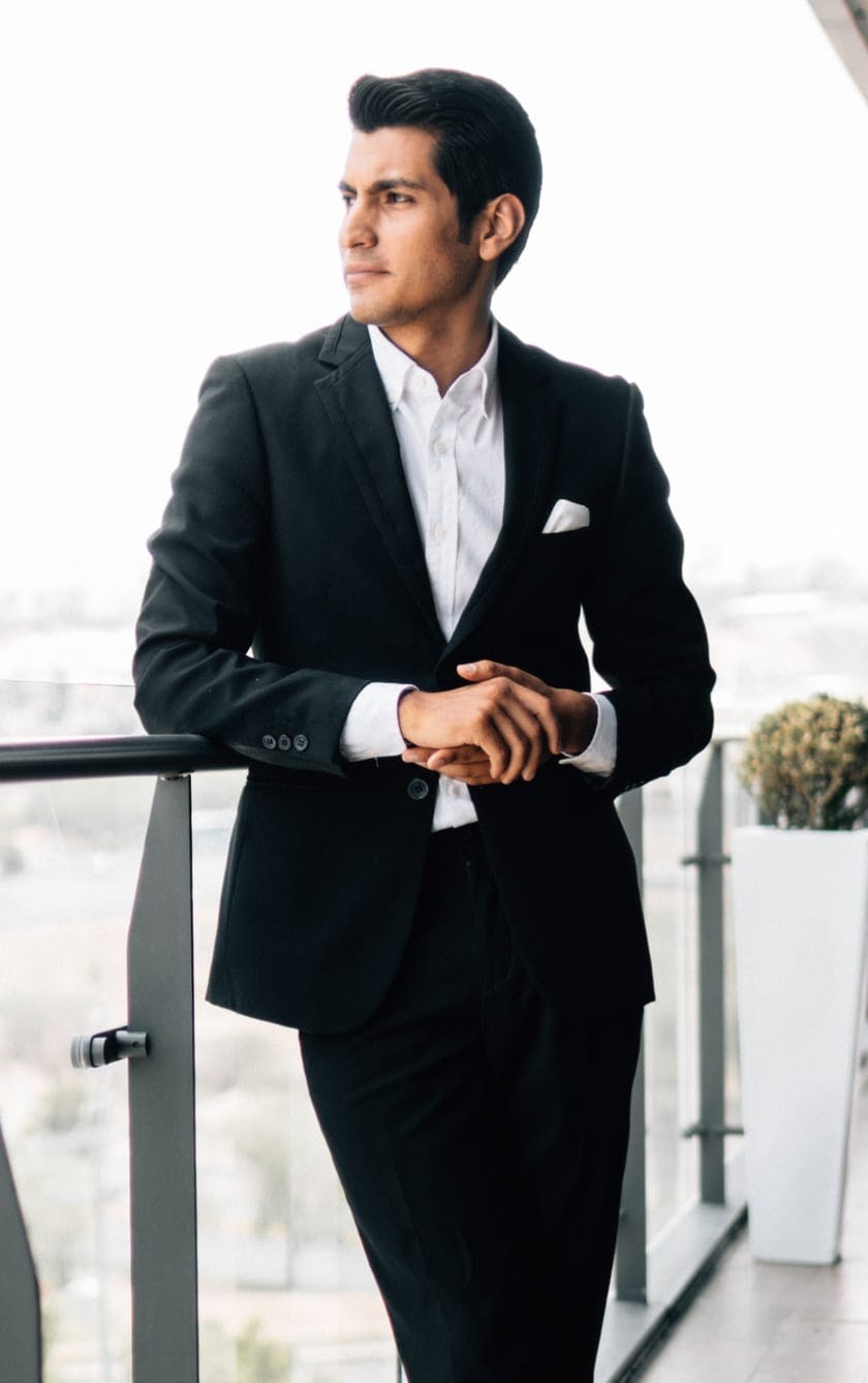 man in suit standing on balcony looking out
