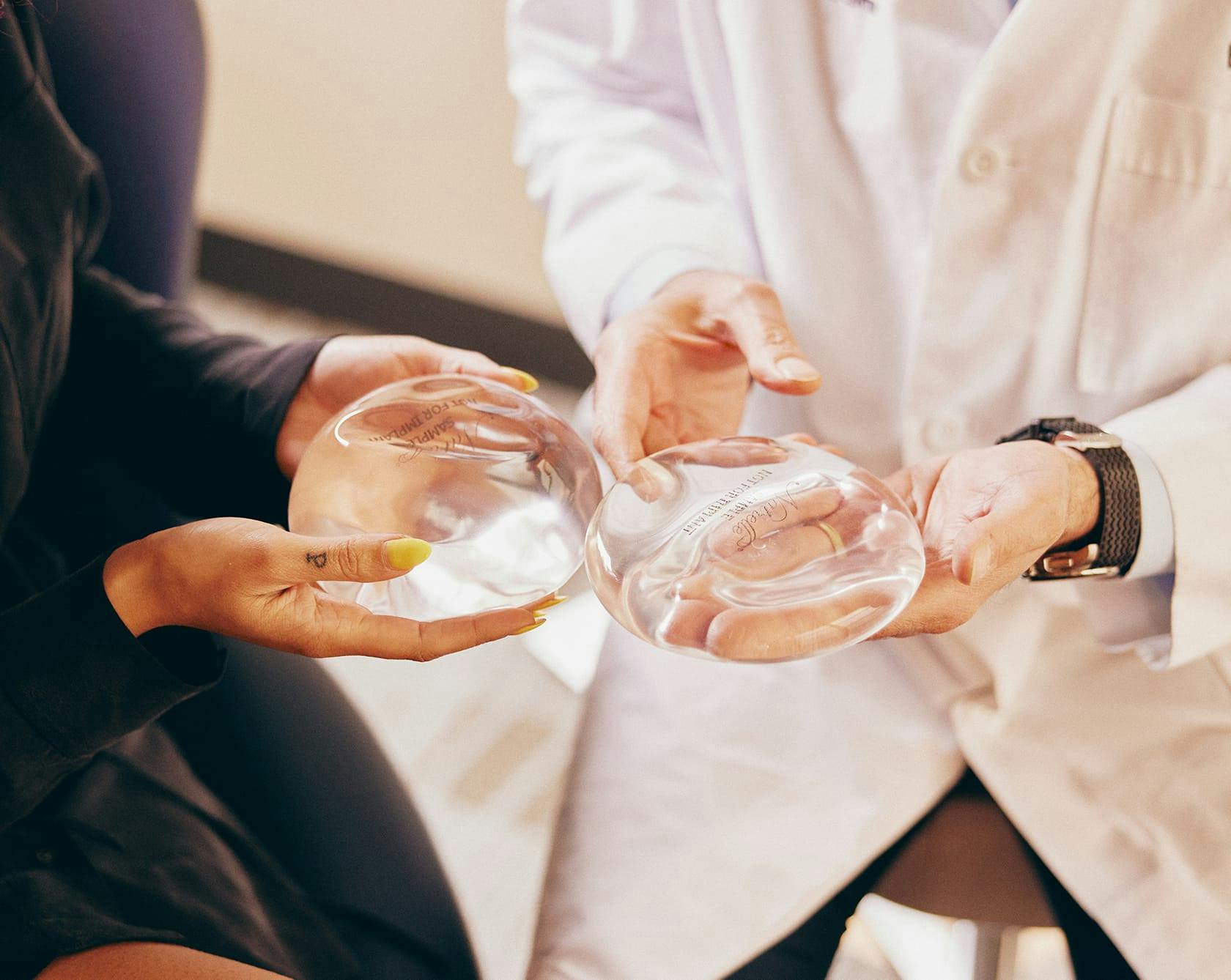 an image of Dr. Egrari showing a woman a breast implant