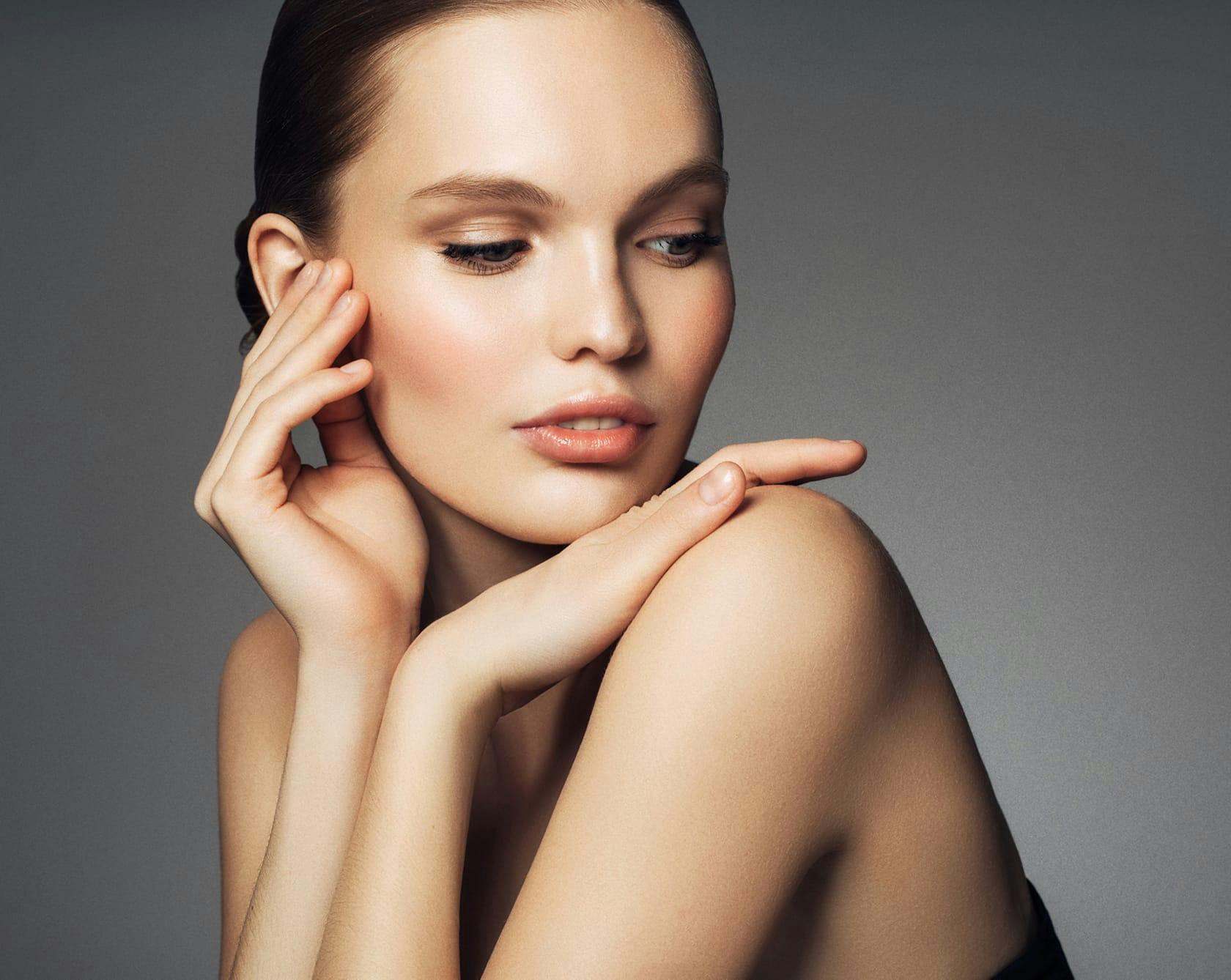 a brunette woman resting her chin and hand on her shoulder