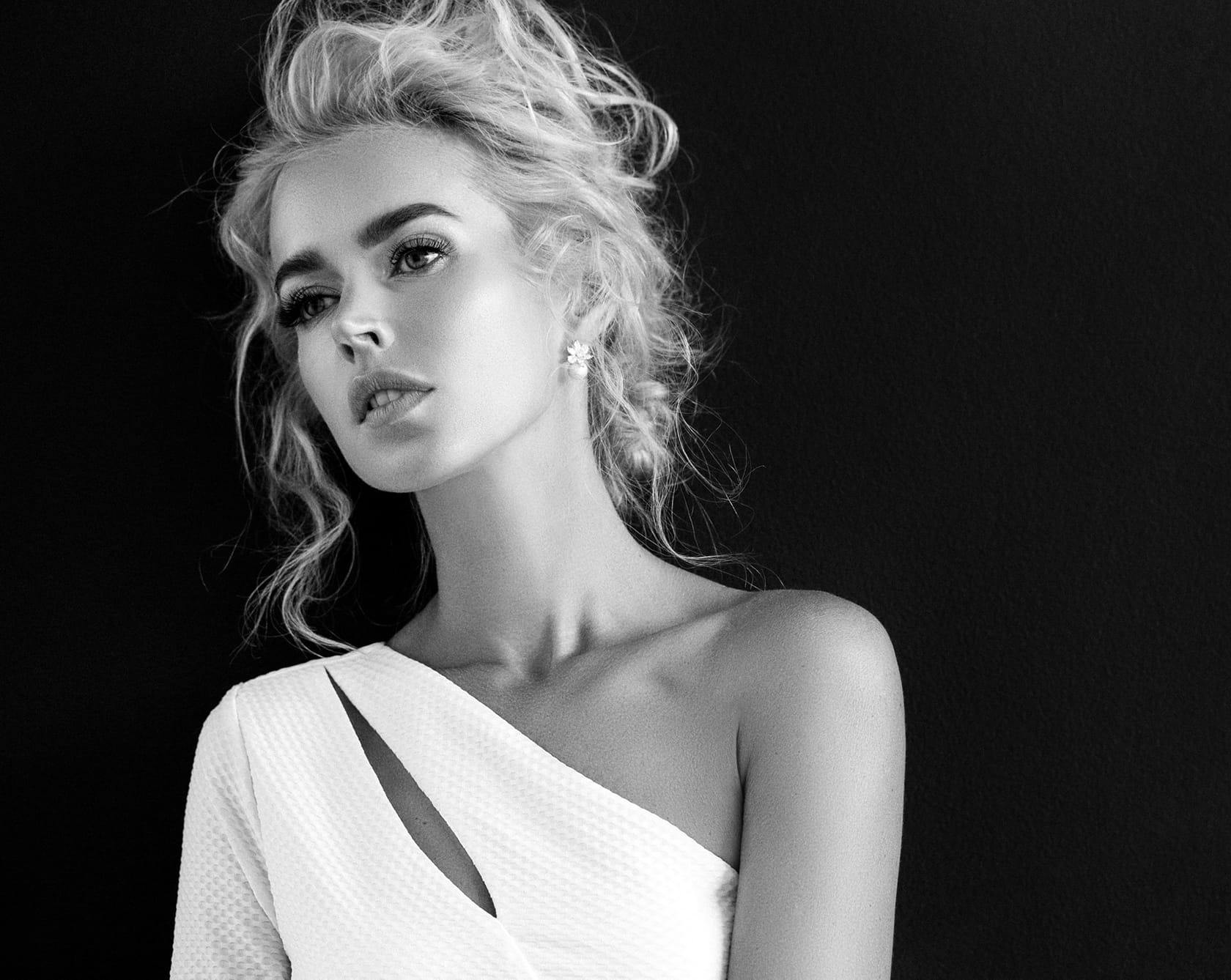a black and white image of a woman in a white top with curly blonde hair