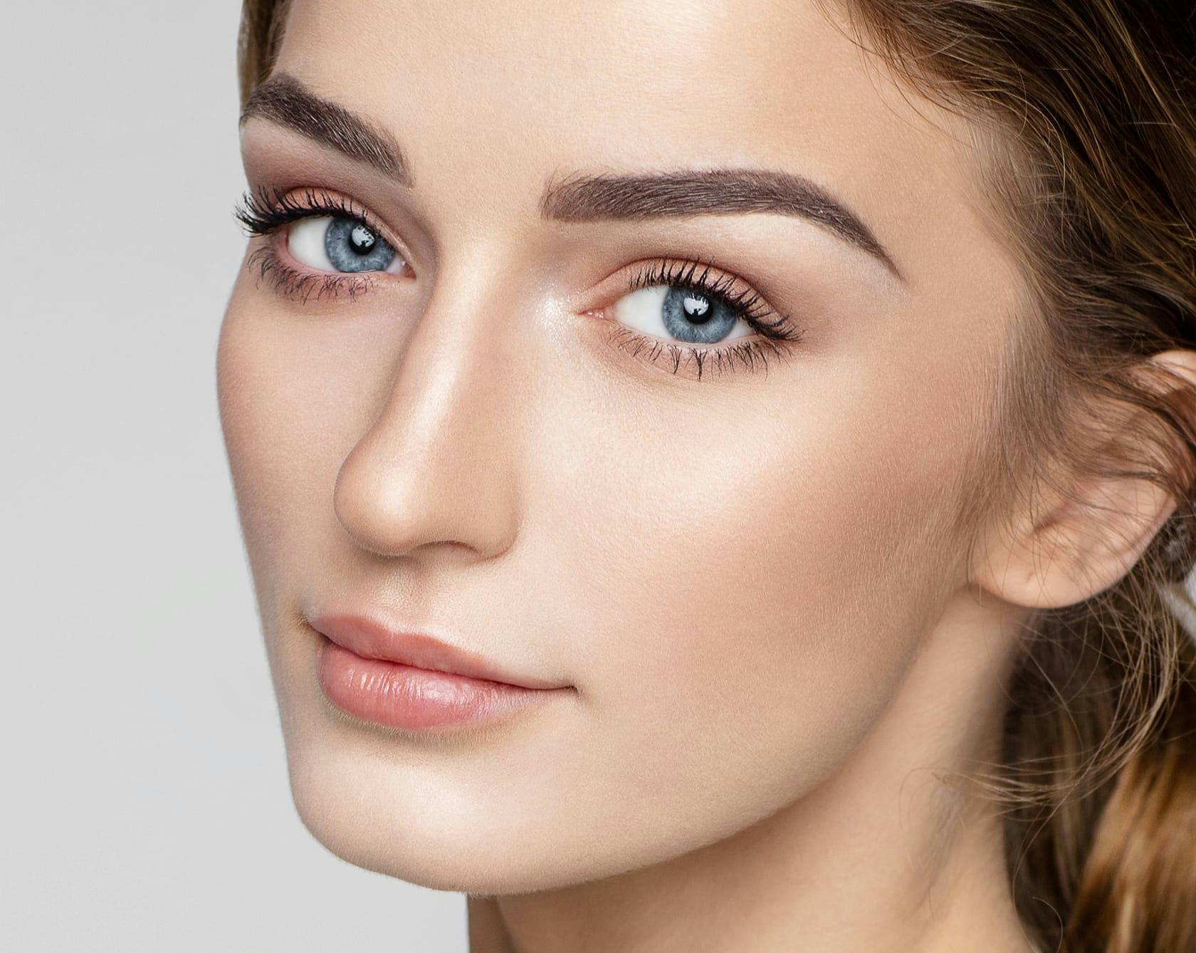 a close up of a woman's face with brunette hair and blue eyes