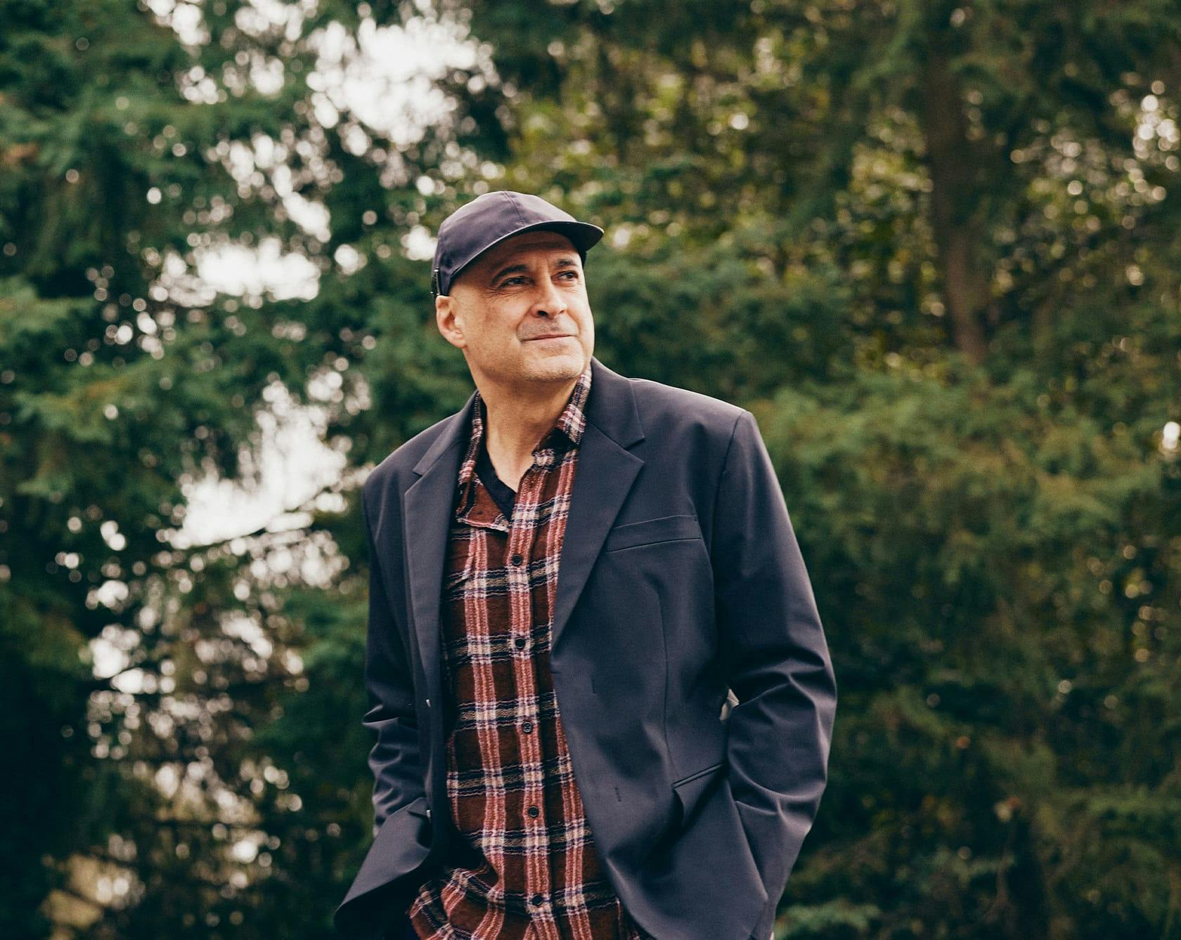 an image of Dr. Egrari in a hair, black blazer, and plaid undershirt