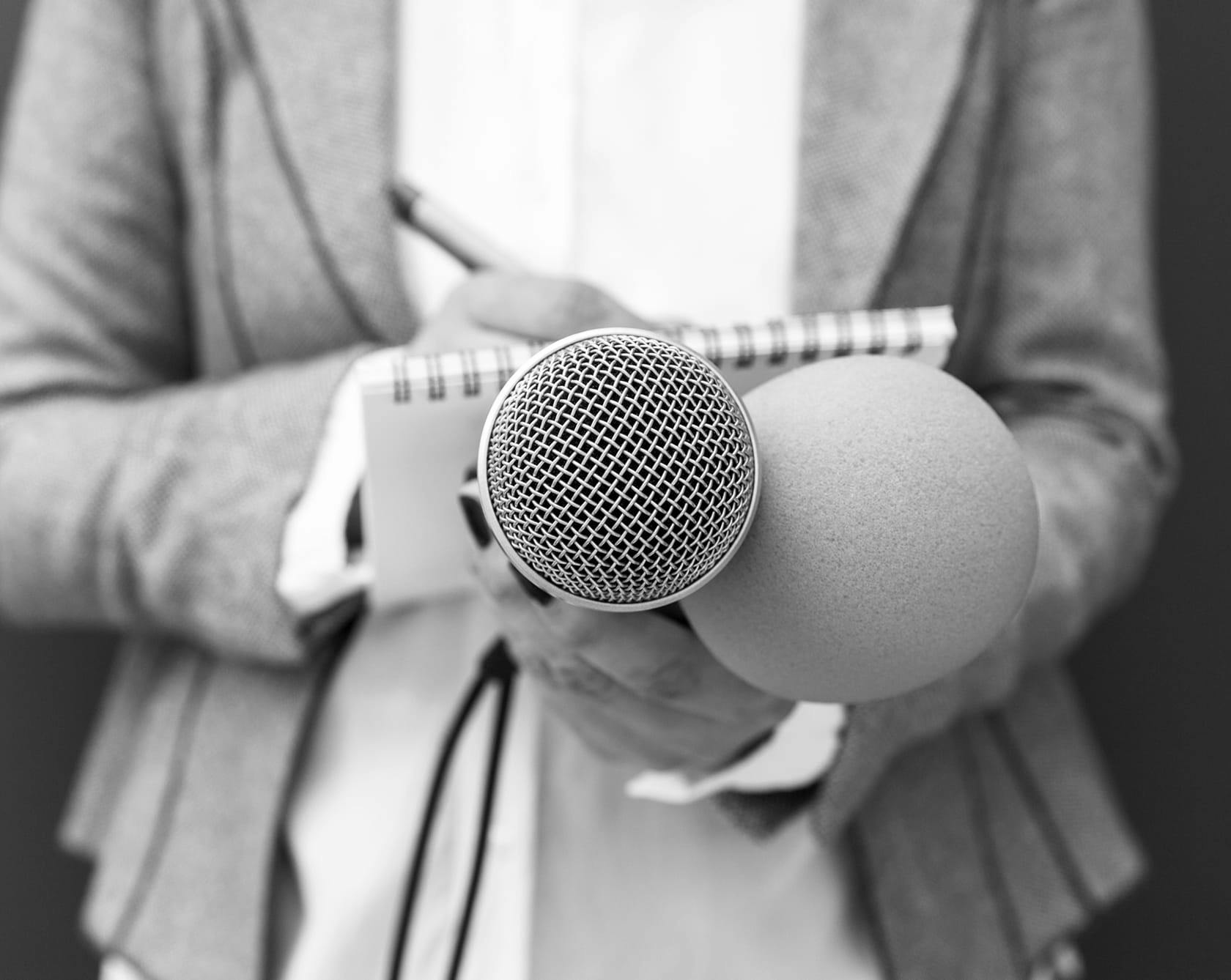 a black and white image of a reporter with a notebook and mic