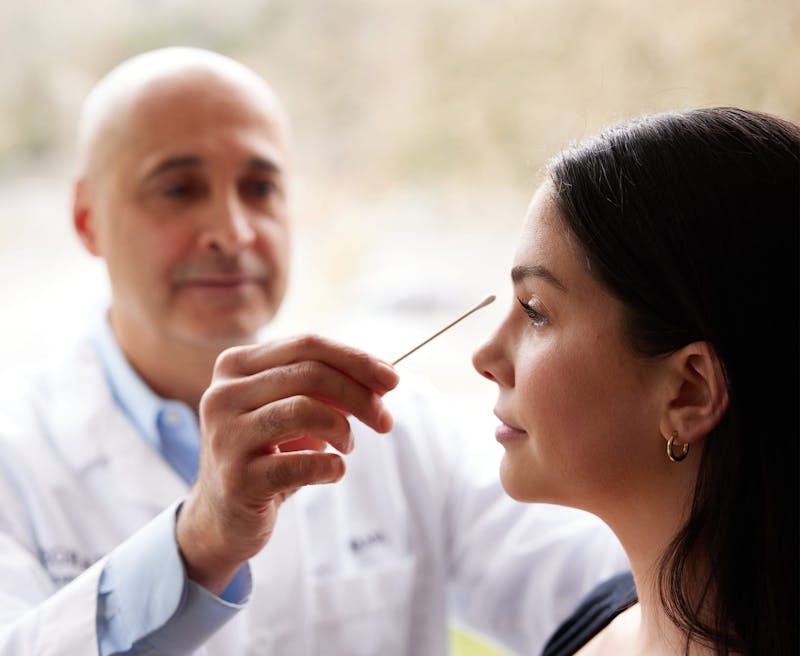 an image of Dr. Egrari doing a facial consultation on a patient