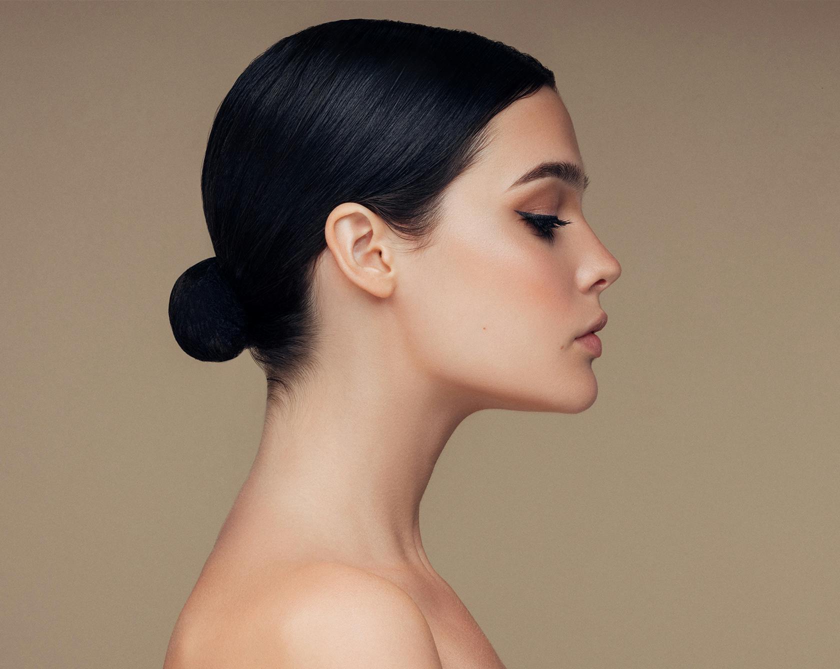 a side view of a woman with hair hair up in a bun