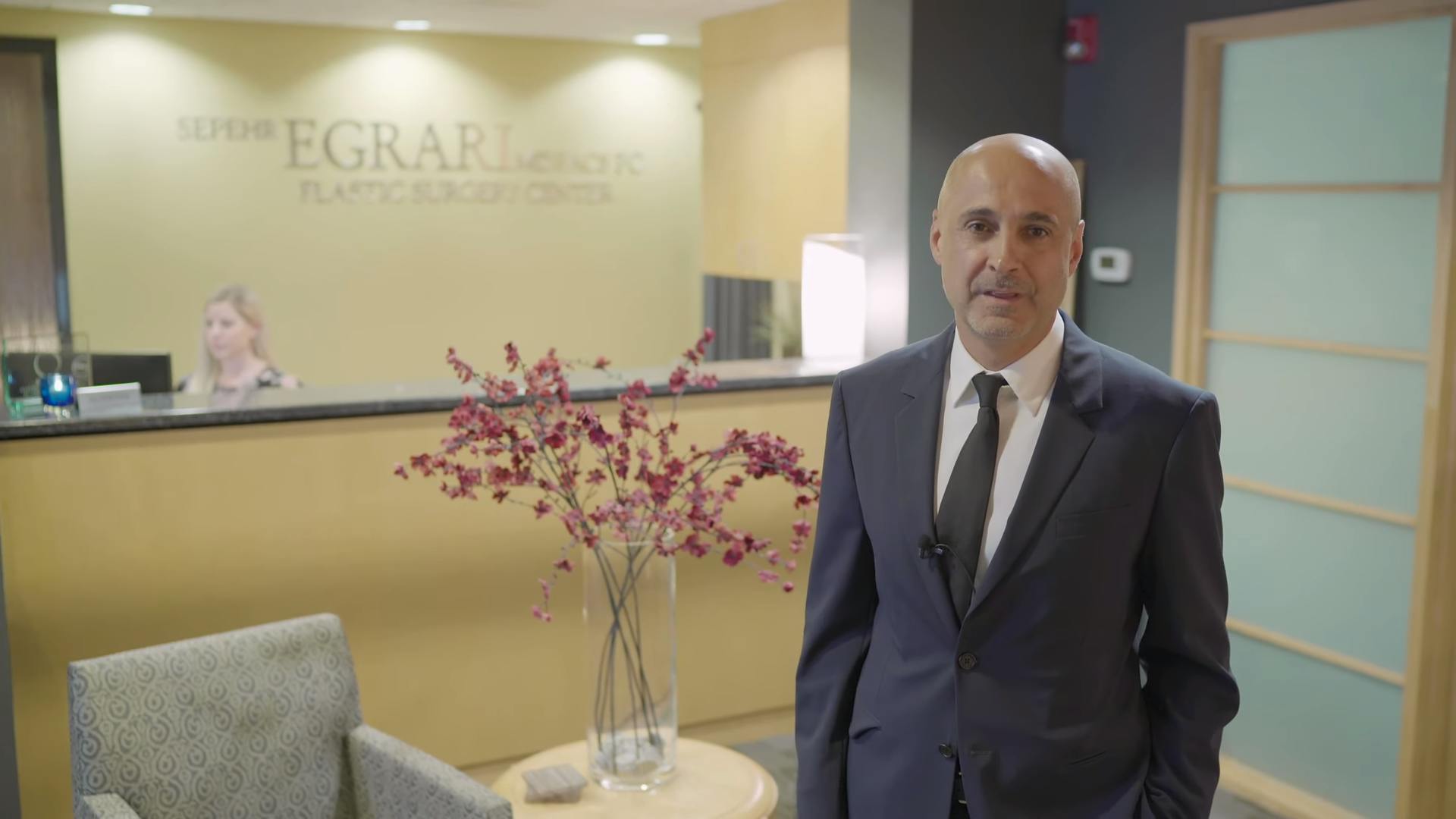 Dr. Egrari  in a suit standing in the lobby of his practice