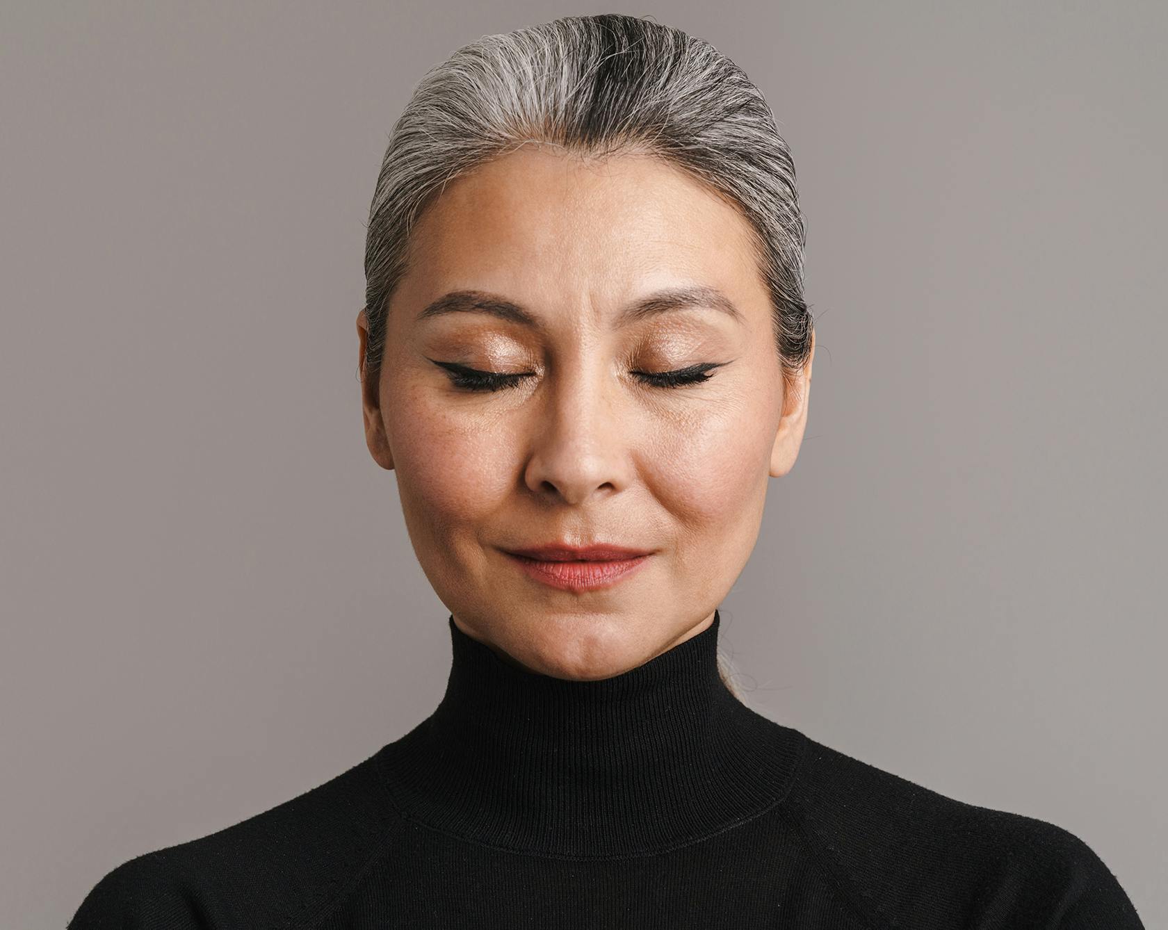 and image of an older asian woman with her eyes closed in a black turtleneck
