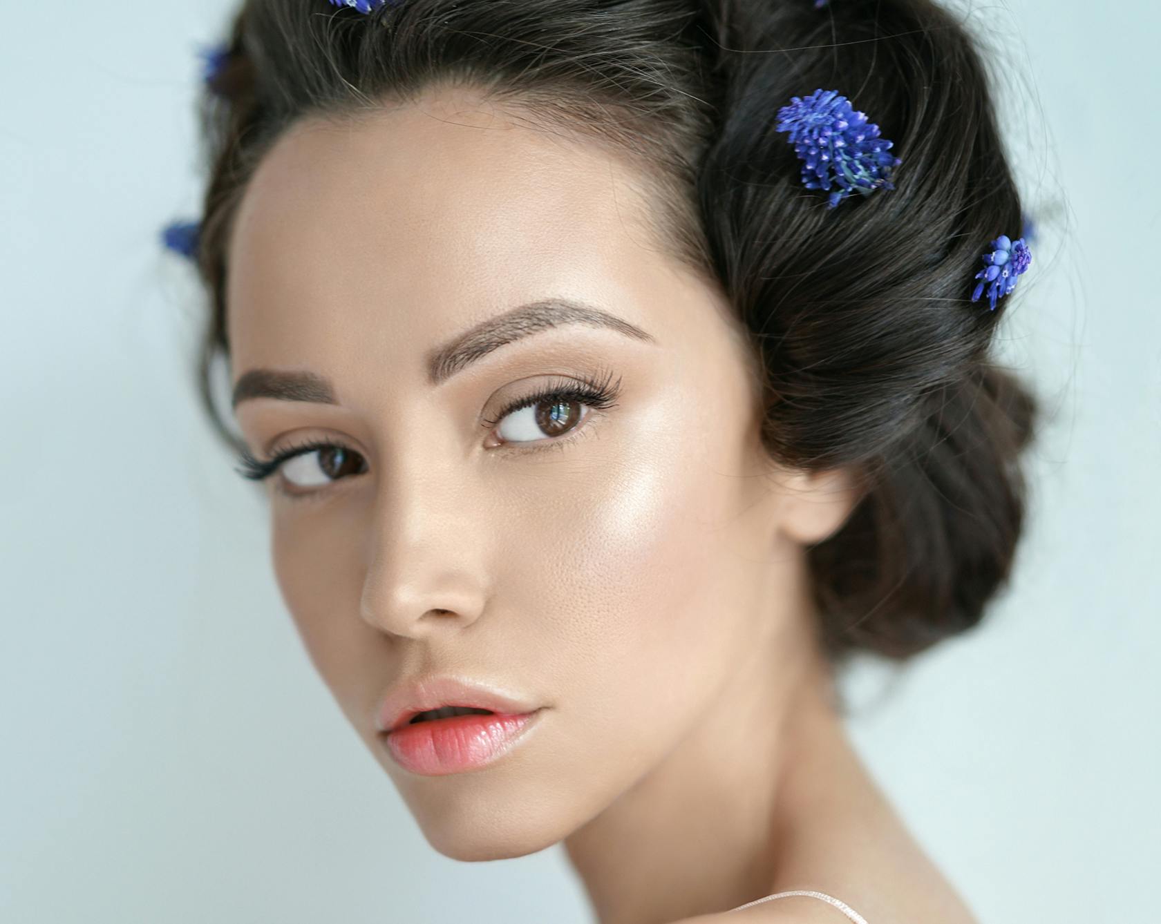 a close up of a woman's face with black hair with blue floral clips