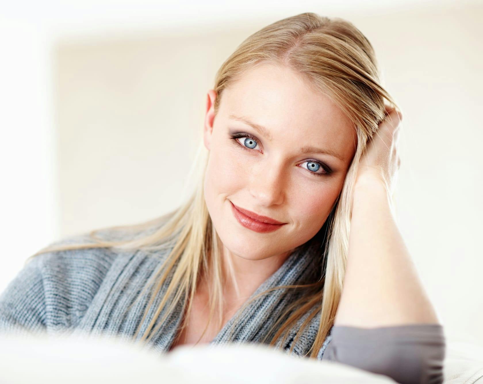 an image of a blonde woman with blue eyes in a grey sweater