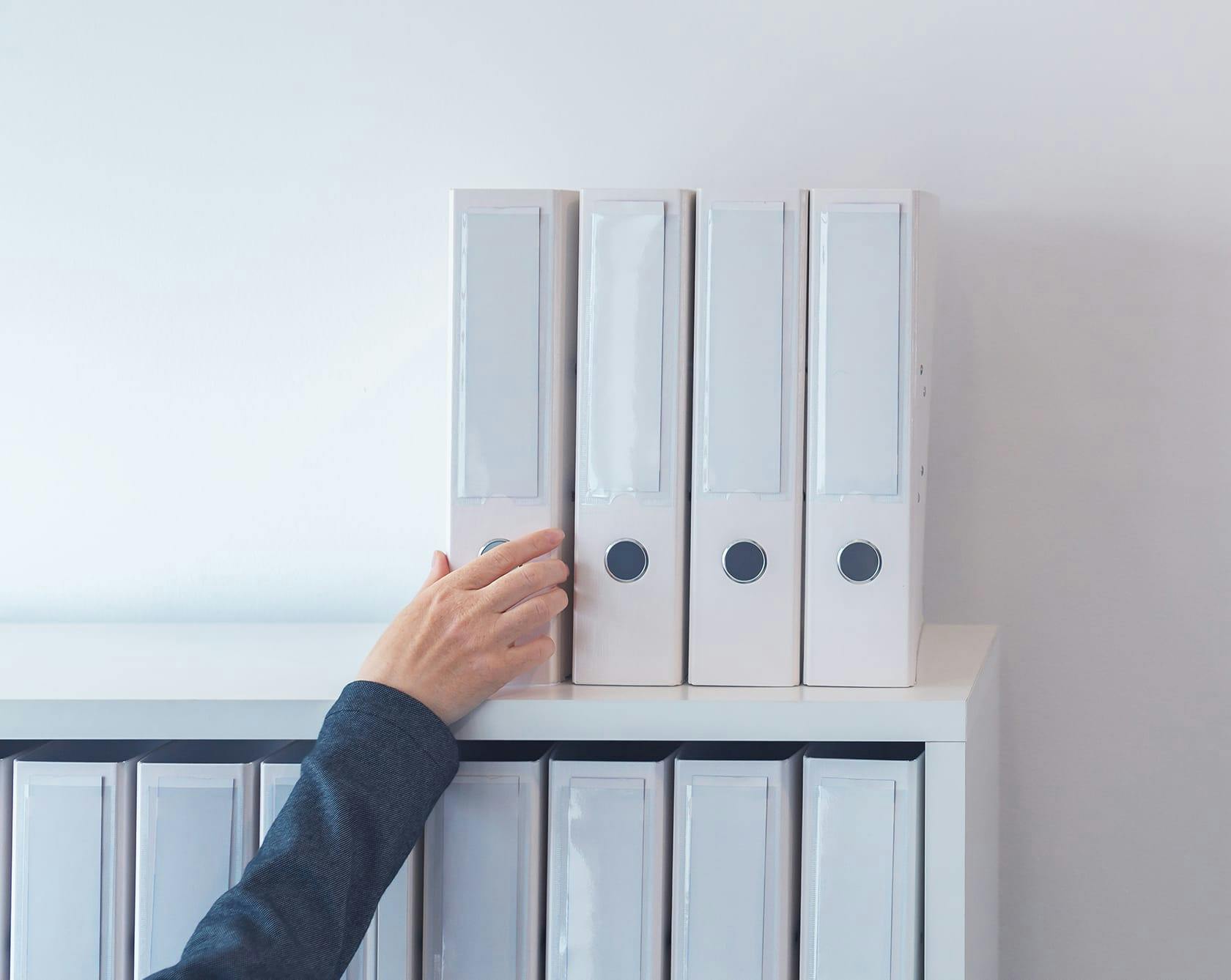 an image of a person reaching for a white binder of information