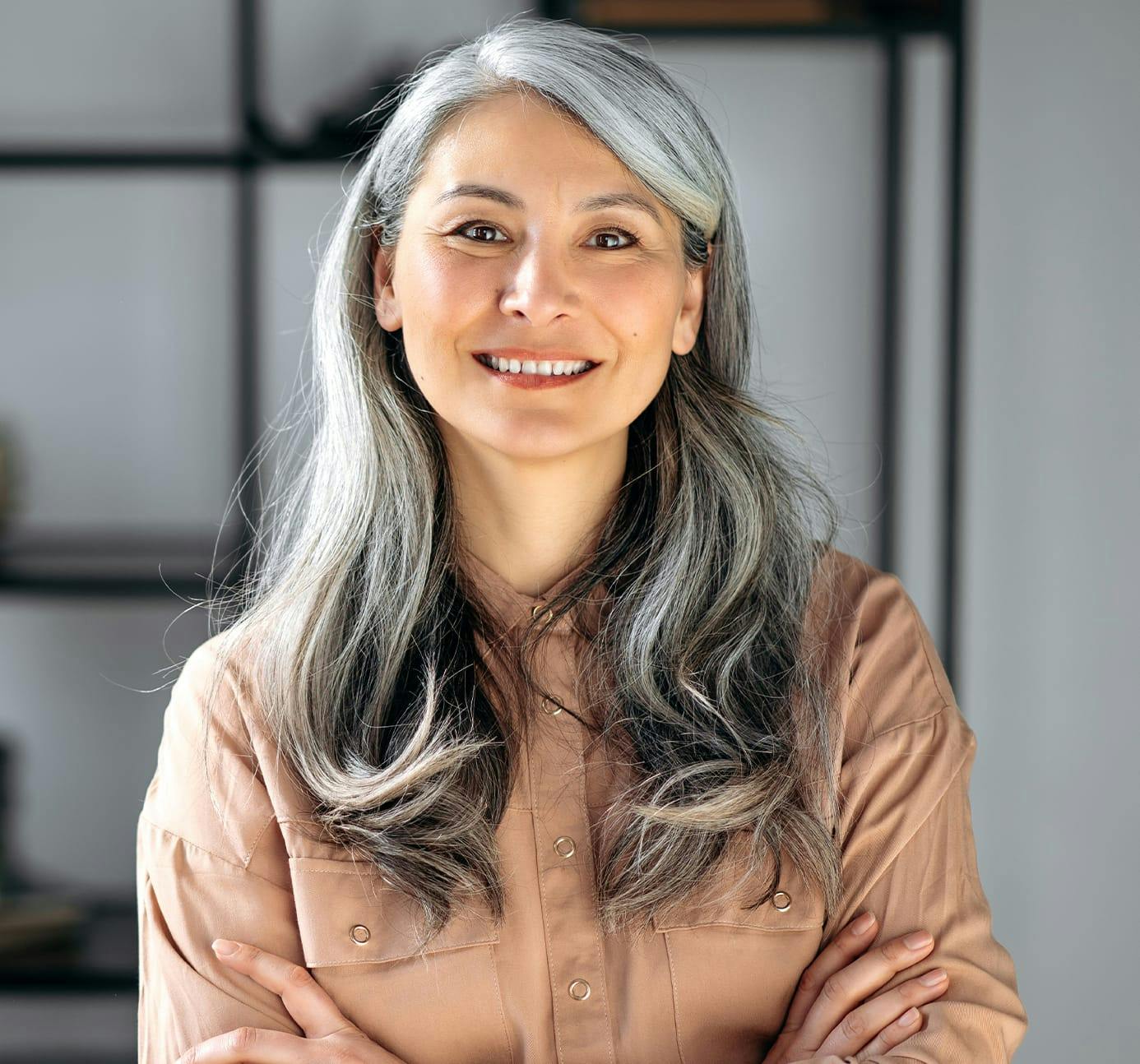 an image of an older woman smiling in a tan buttondown